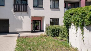 Ein mehrgeschossiges Wohngebäude mit geschlossenem Eingangsbereich und einem kleinen Garten.