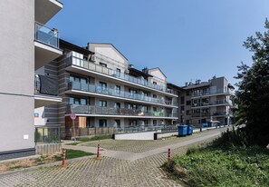 Ein mehrgeschossiges Wohngebäude mit Balkonen, einem gepflasterten Gehweg und einem Verbotsschild für Fahrzeuge.