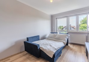 Een slaapkamer met een bed, twee stoelen, een raam en een radiator.