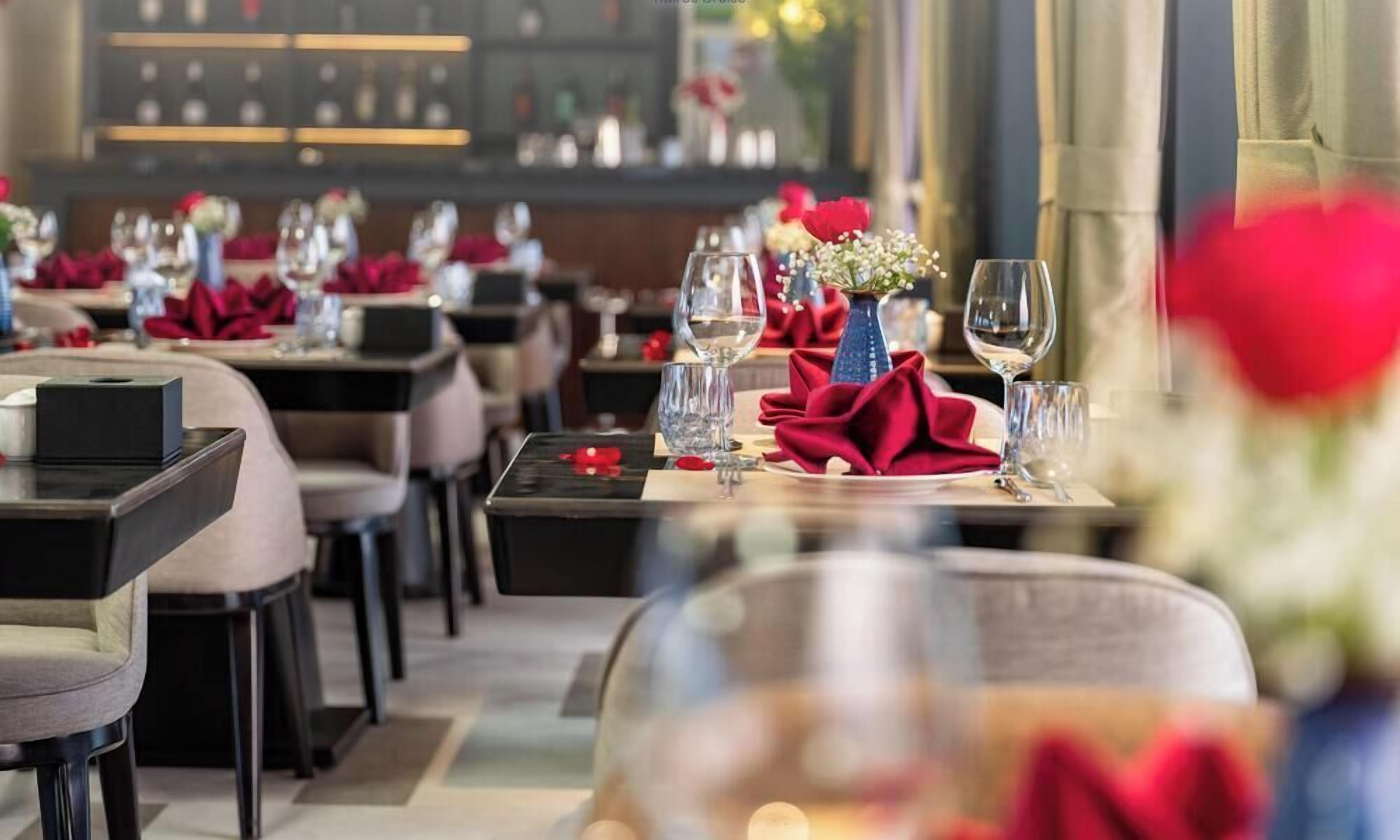 Un restaurante con mesas dispuestas para comer, destacando servilletas rojas y copas de vidrio transparentes.