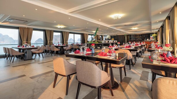 Ein Restaurant mit mehreren Tischen, Stühlen und Meerblick.