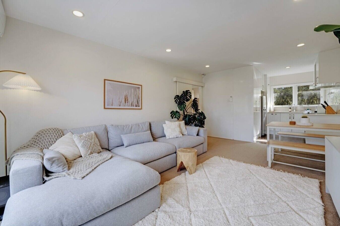 A modern living room with a grey sectional sofa, a white rug, and a wooden coffee table.