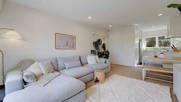A modern living room with a grey sectional sofa, a white rug, and a wooden coffee table.