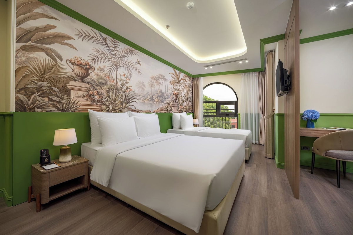 Habitación de hotel con una cama grande, un escritorio, una silla, un televisor y un mural en la pared.