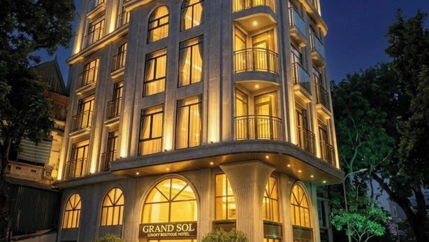 A multi-story hotel with a grand entrance, large windows, and a crescent moon in the background. - Grand Sol Luxury Boutique Hotel (Hanoi)