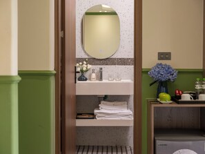 Un baño con espejo, lavamanos y toallero.