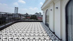 A balcony with a geometric tile floor, a metal railing, and a view of buildings in the distance. - Grand Sol Luxury Boutique Hotel (Hanoi)