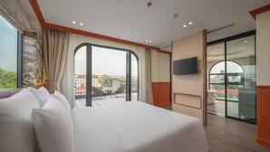 A hotel room with a large bed, a TV mounted on the wall, and a balcony with a view of the city. - Grand Sol Luxury Boutique Hotel (Hanoi)