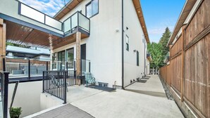 A modern building with a covered patio, a wooden fence, and a paved walkway.