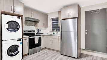 A compact kitchen with a washing machine, oven, and refrigerator.