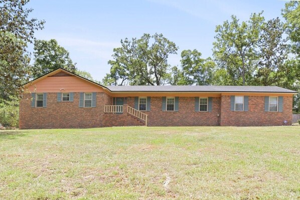 A single-story brick house with a front porch and a small staircase leading to the entrance.