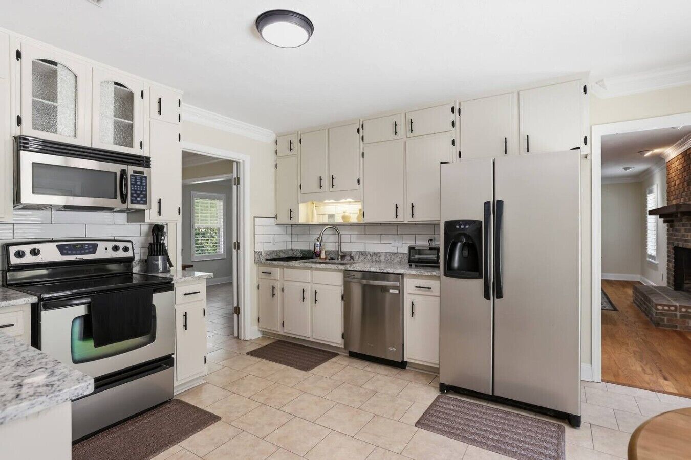 A modern kitchen with stainless steel appliances, white cabinetry, and a built-in oven.