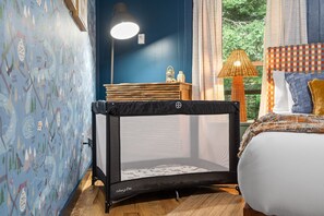Et værelse med en seng, en tremmeseng, en lampe og en væg med et verdenskort-design.