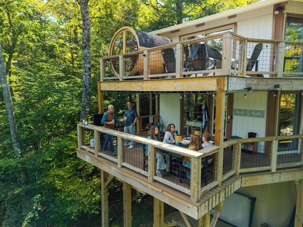 Ein zweistöckiges Holzhaus mit Balkon, umgeben von Bäumen.