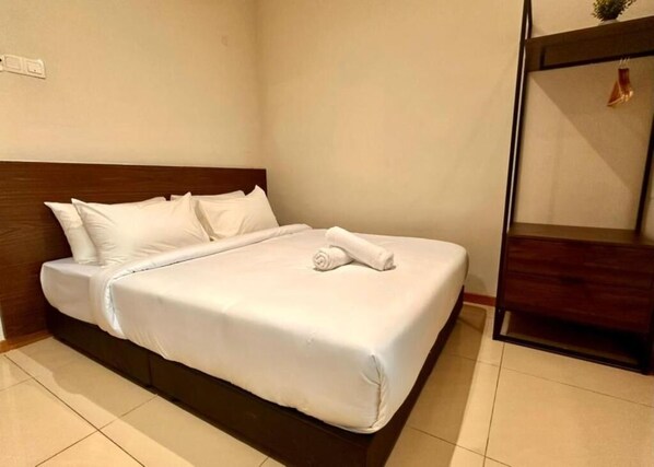A neatly made bed with white linens and a rolled towel, a wooden headboard, and a small wooden nightstand with a drawer. - Swing & Pillows @ Chow Kit Road, Kuala Lumpur (Kuala Lumpur)