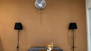 Una habitación con una pared marrón, una mesa redonda con un florero y dos lámparas de pie.
