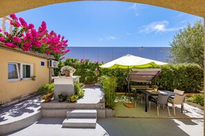 A patio with a table and chairs under a canopy, surrounded by potted plants and a wall with a window. - Zadar Studio Klaric 2 /w Garden, Zadar, Croatia (Zadar)