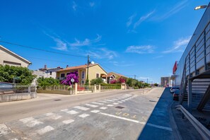 Une vue de rue avec un bâtiment dont le toit est recouvert de tuiles rouges et la façade est jaune.