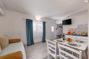 A compact living space with a kitchenette, a dining area, and a seating area with a sofa. - Zadar App Klaric 1 with Garden, Zadar, Croatia (Zadar)