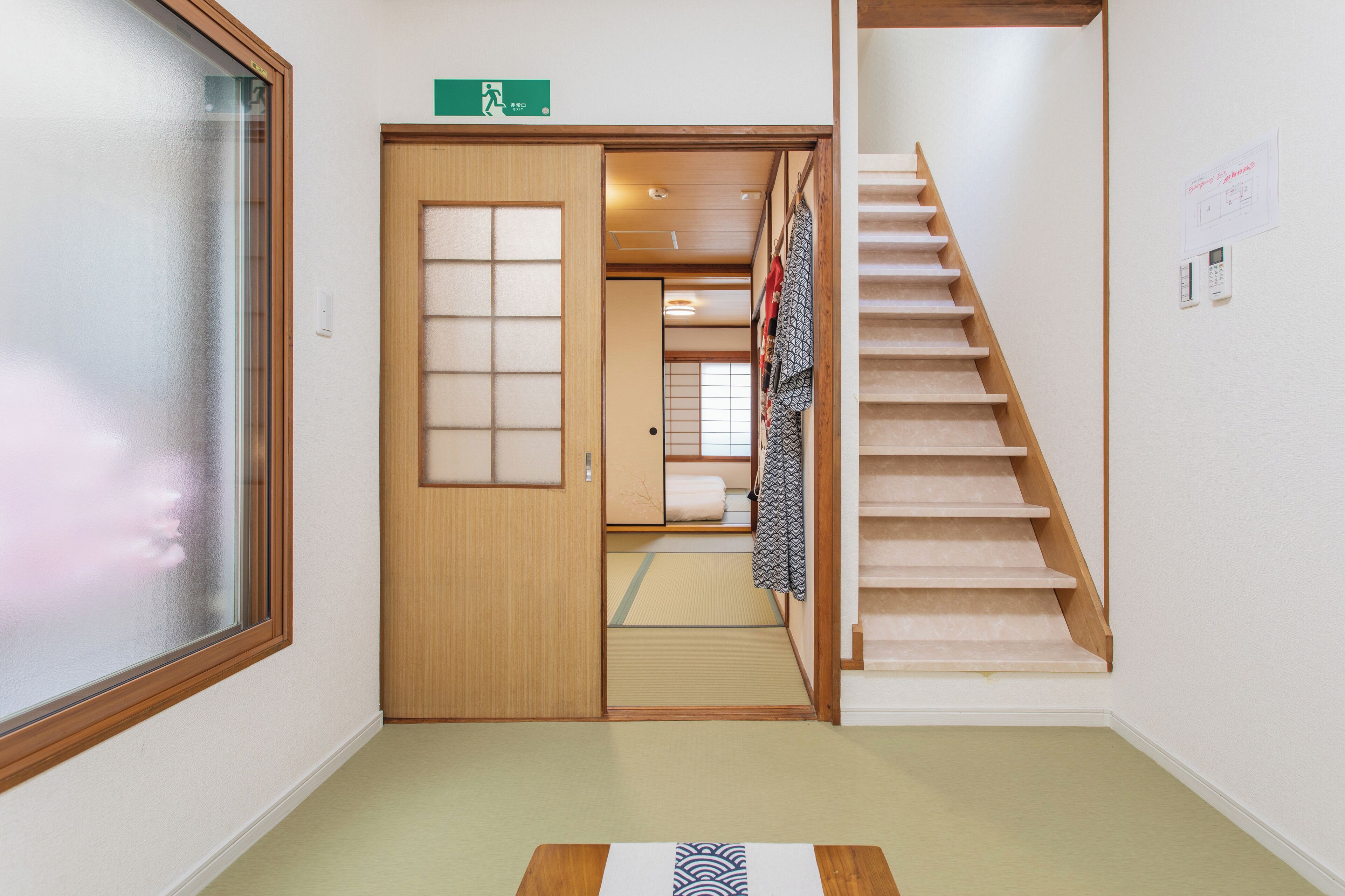 A hotel hallway with a wooden door, a staircase, and a tatami mat.