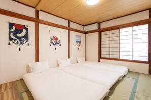 A traditional Japanese room with tatami flooring, a futon bed, shoji screens, and artwork on the walls. - Midoribashi (Osaka)