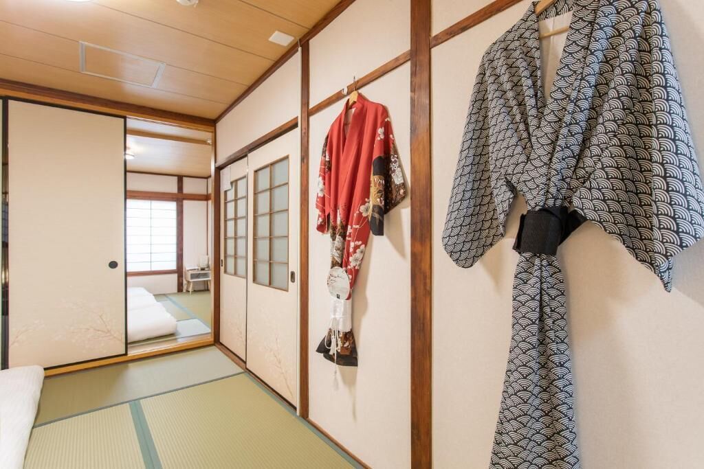 A traditional Japanese room with tatami flooring, sliding doors, and a bed with white bedding.