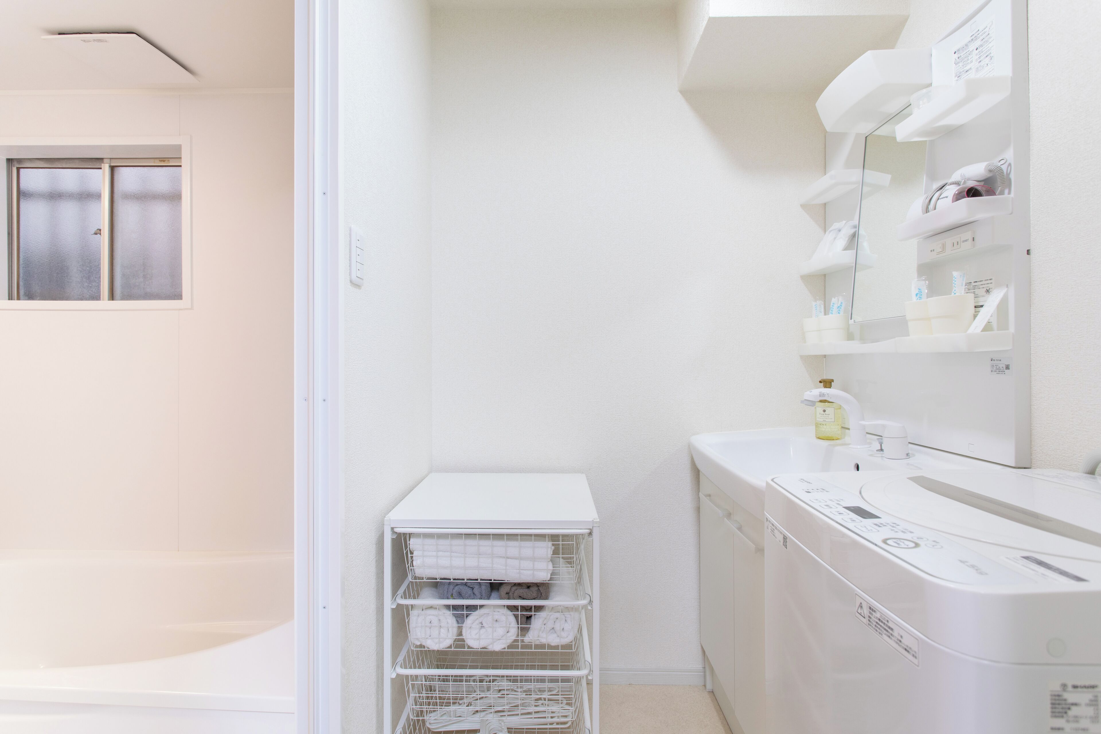 A clean, modern bathroom with a white sink, mirror, and towel rack.