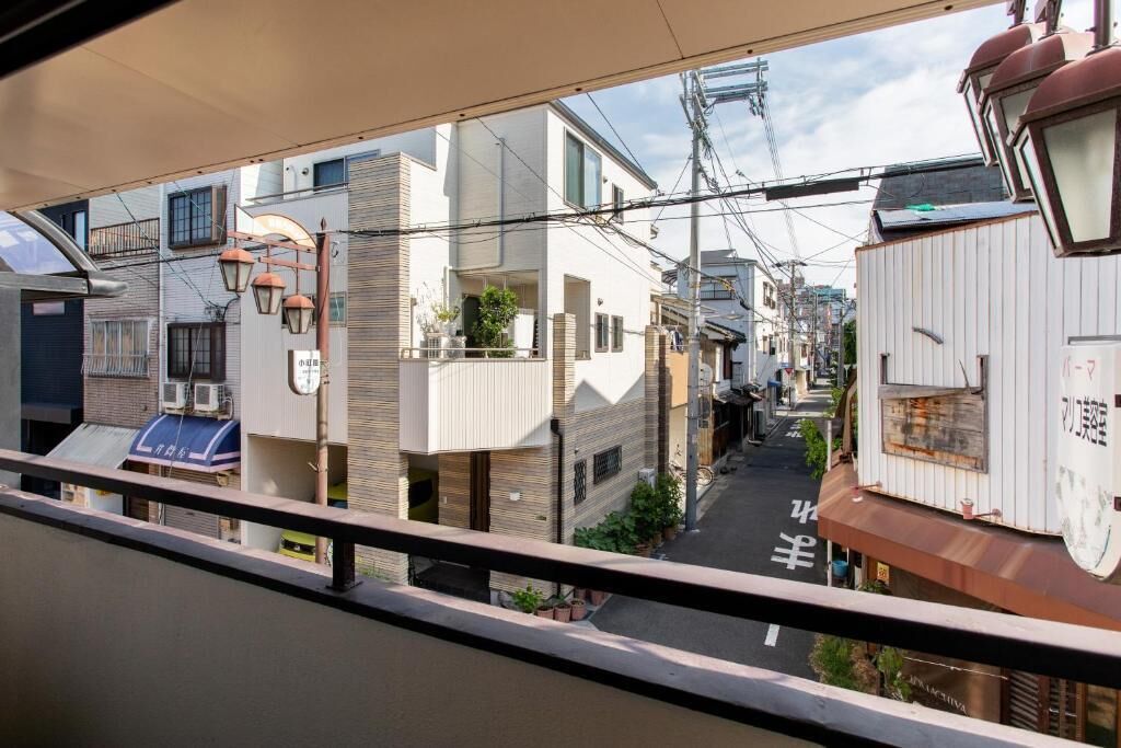 A narrow urban street with residential buildings, a visible clock, and overhead power lines.