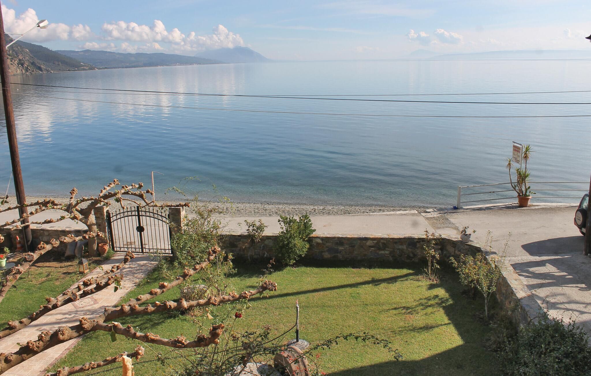 A lakeside property with a paved walkway, a stone wall, and a view of the lake.