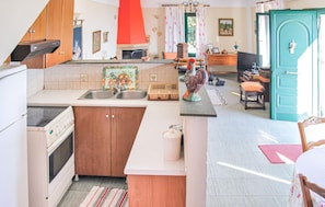 A kitchen with a stove, sink, and a decorative rooster. There's a dining area with a table and chairs.