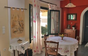 A dining area with a round table, chairs, a small table with a bowl, and a wall-mounted light fixture. - Cozy home in Loutra Aidipsou with WiFi (Loutra Aidipsou)