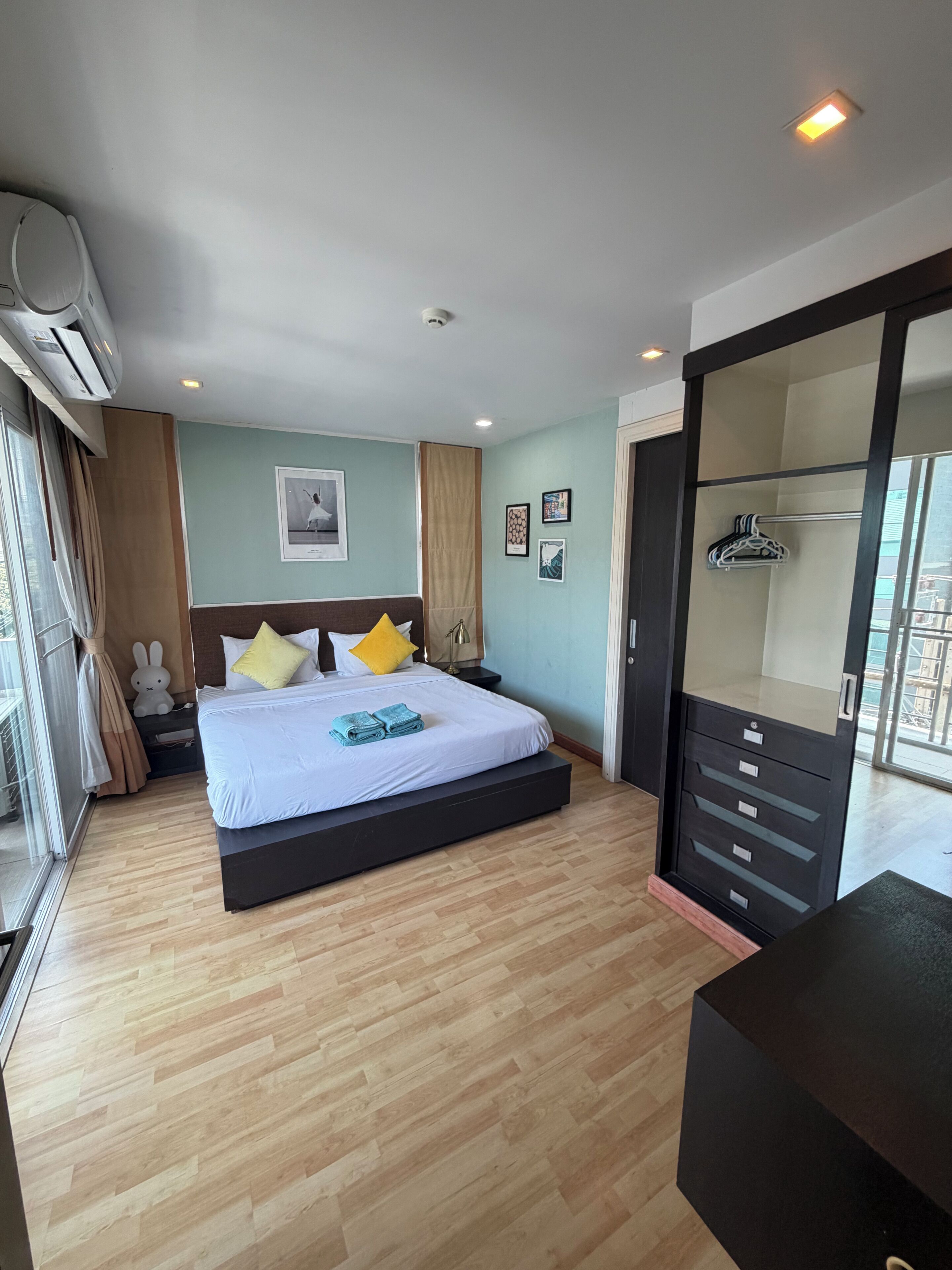 Une chambre d’hôtel avec un lit, une armoire, un bureau et une grande fenêtre.