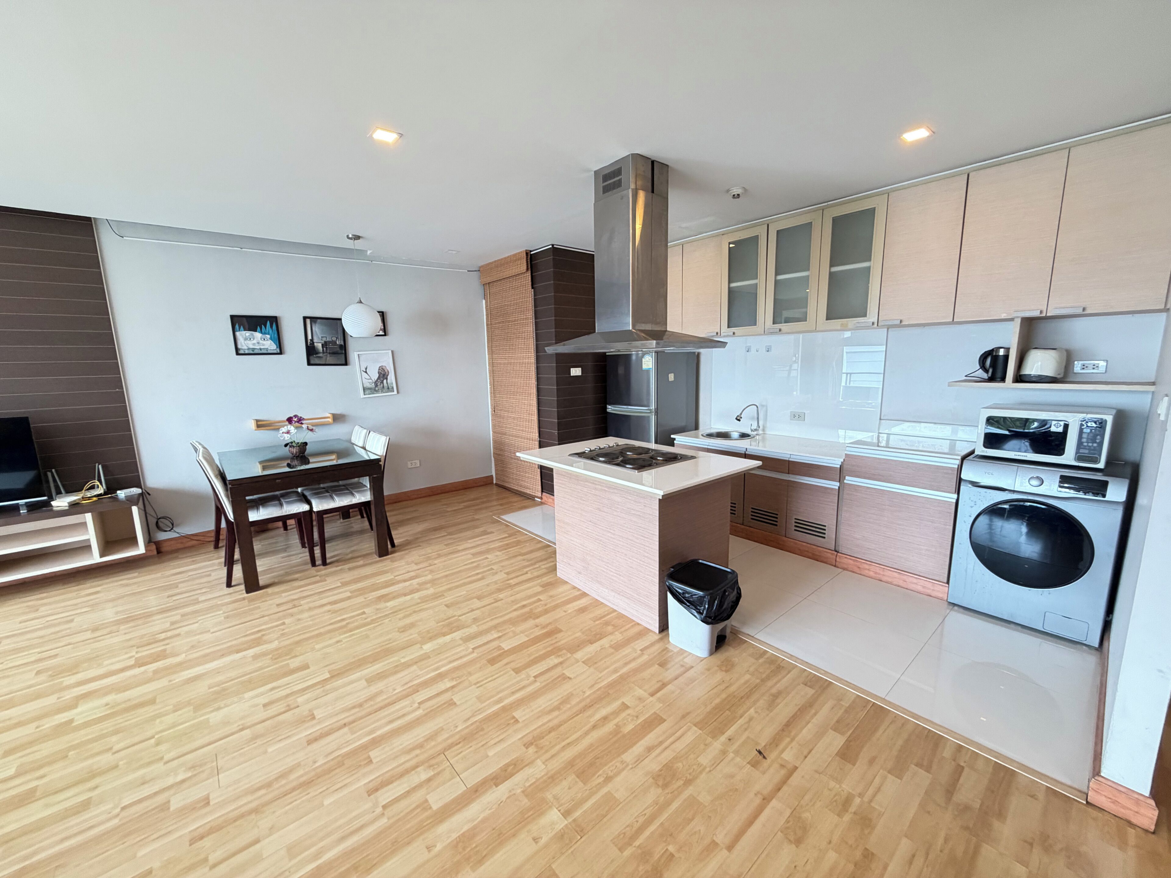 A modern kitchen with a central island, built-in appliances, and a dining area with a table and chairs.