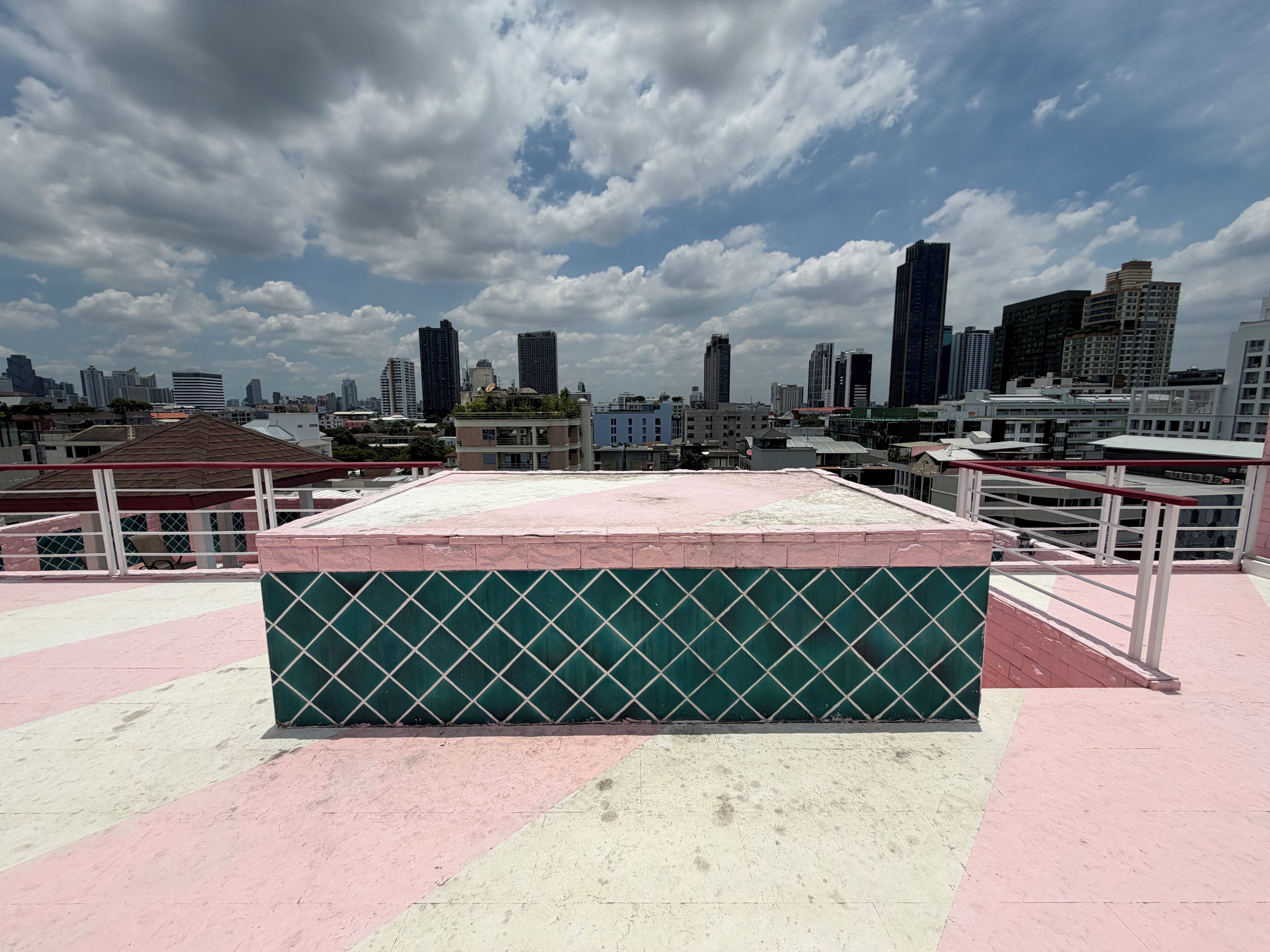 Eine Dachterrasse mit Blick auf eine Stadtlandschaft, mit einer Mischung aus Hochhäusern und blauem Himmel.