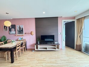 A modern living room with a flat-screen TV, wooden flooring, and a dining area with a table and chairs. - P Residence Thonglor  (Bangkok)