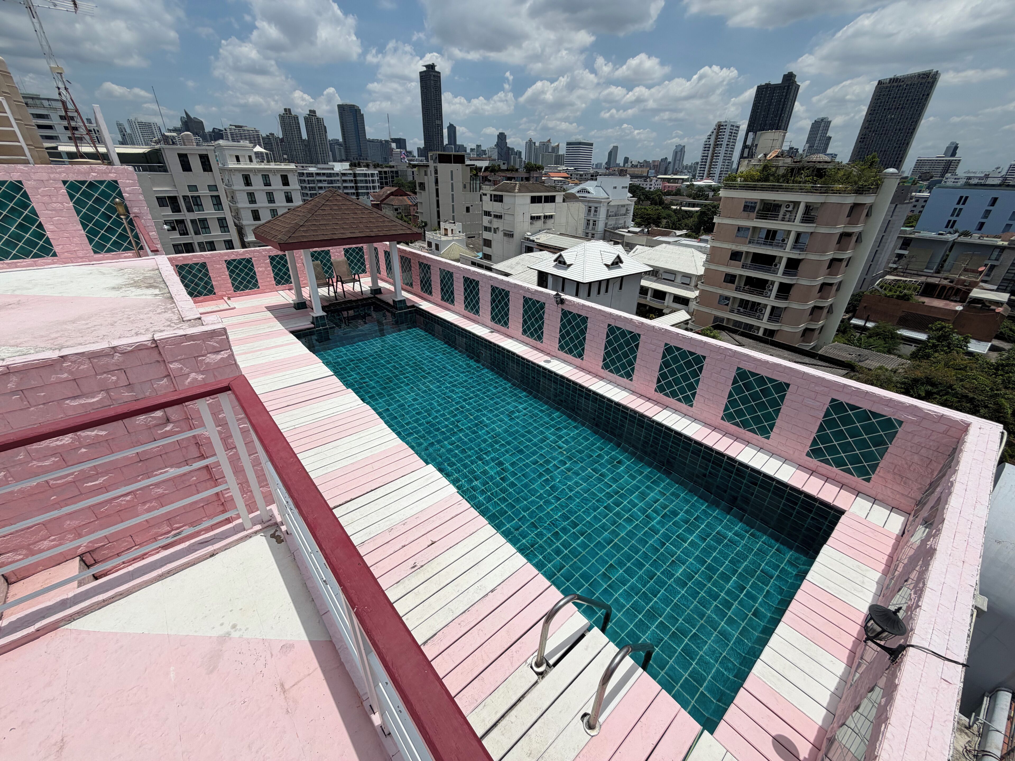 A rooftop swimming pool with a cityscape view, surrounded by buildings.
