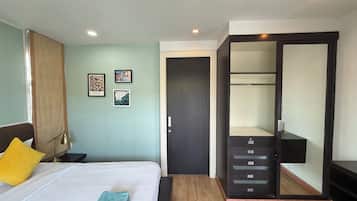 A hotel room with a bed, bedside table, lamp, and a wardrobe with a mirror.