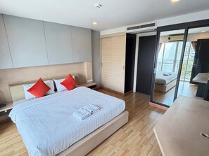 A modern hotel room with a large bed, a bedside table, a wardrobe, and a sliding door leading to a balcony. - P Residence Thonglor  (Bangkok)