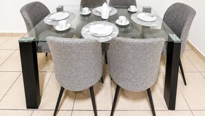 A conference room with a glass table, grey upholstered chairs, and white plates set for a meeting.