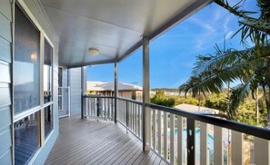 Ein überdachter Balkon mit Blick auf ein Schwimmbad und Palmen.