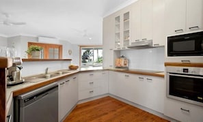 Eine moderne Küche mit weißen Schränken, einem Geschirrspüler, einem Backofen und einer Mikrowelle.