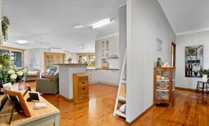 A spacious living area with a wooden floor, a sofa, a coffee table, and a cabinet.