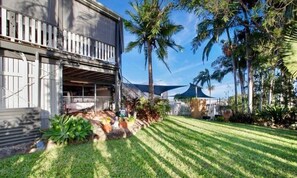 A building with a covered outdoor area, a well-maintained lawn, and palm trees.