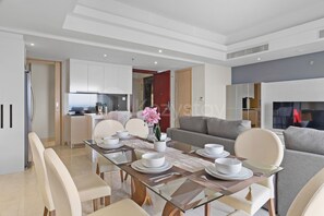 A modern dining area with a glass table, white chairs, and a central orchid plant. - Cavren by Kozystay - MERR (Surabaya)