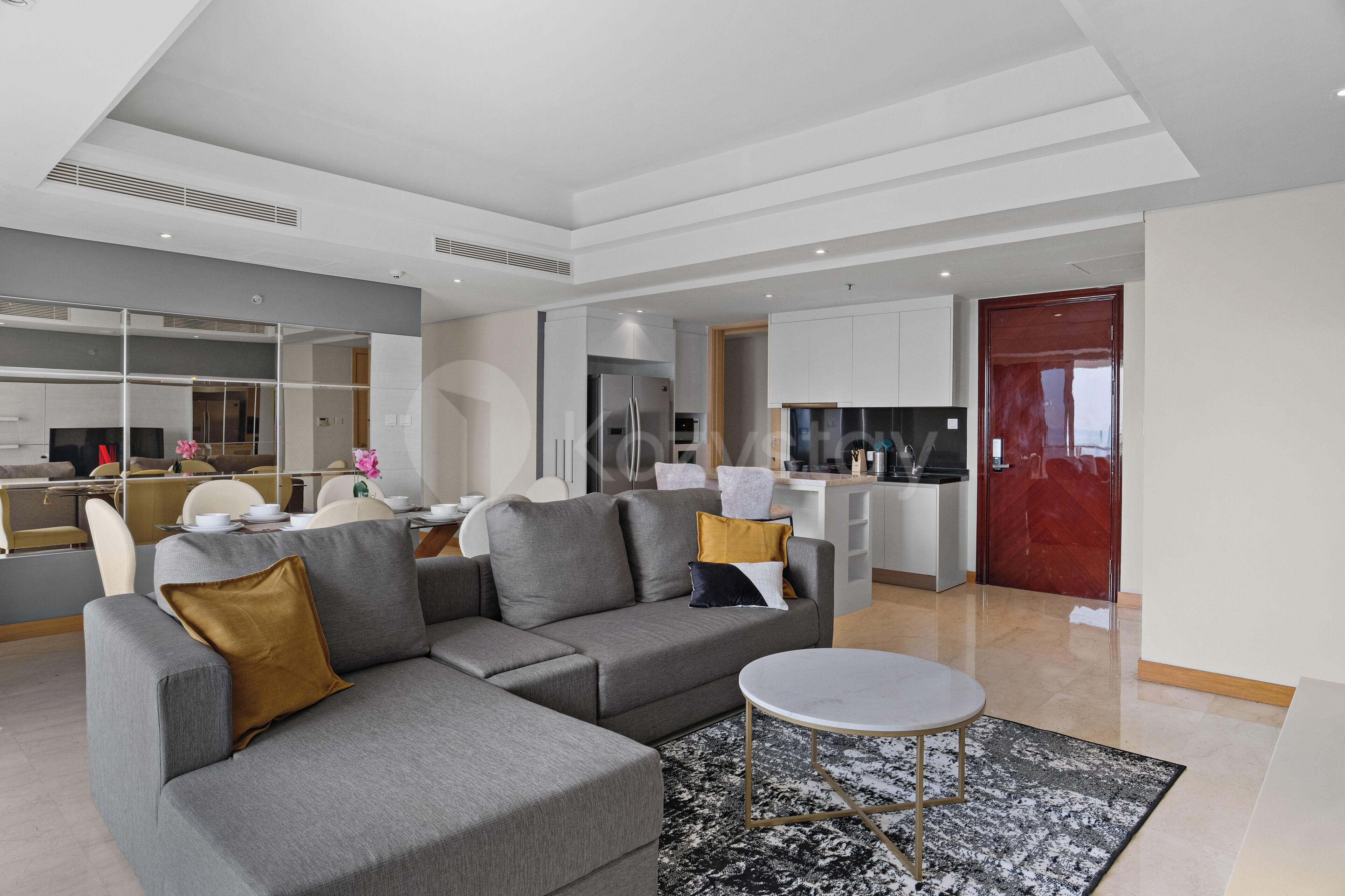 A modern living room with a sectional sofa, a round coffee table, and a dining area with chairs and a table.