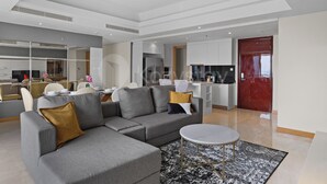 A modern living room with a sectional sofa, a round coffee table, and a dining area with chairs and a table. - Cavren by Kozystay - MERR (Surabaya)