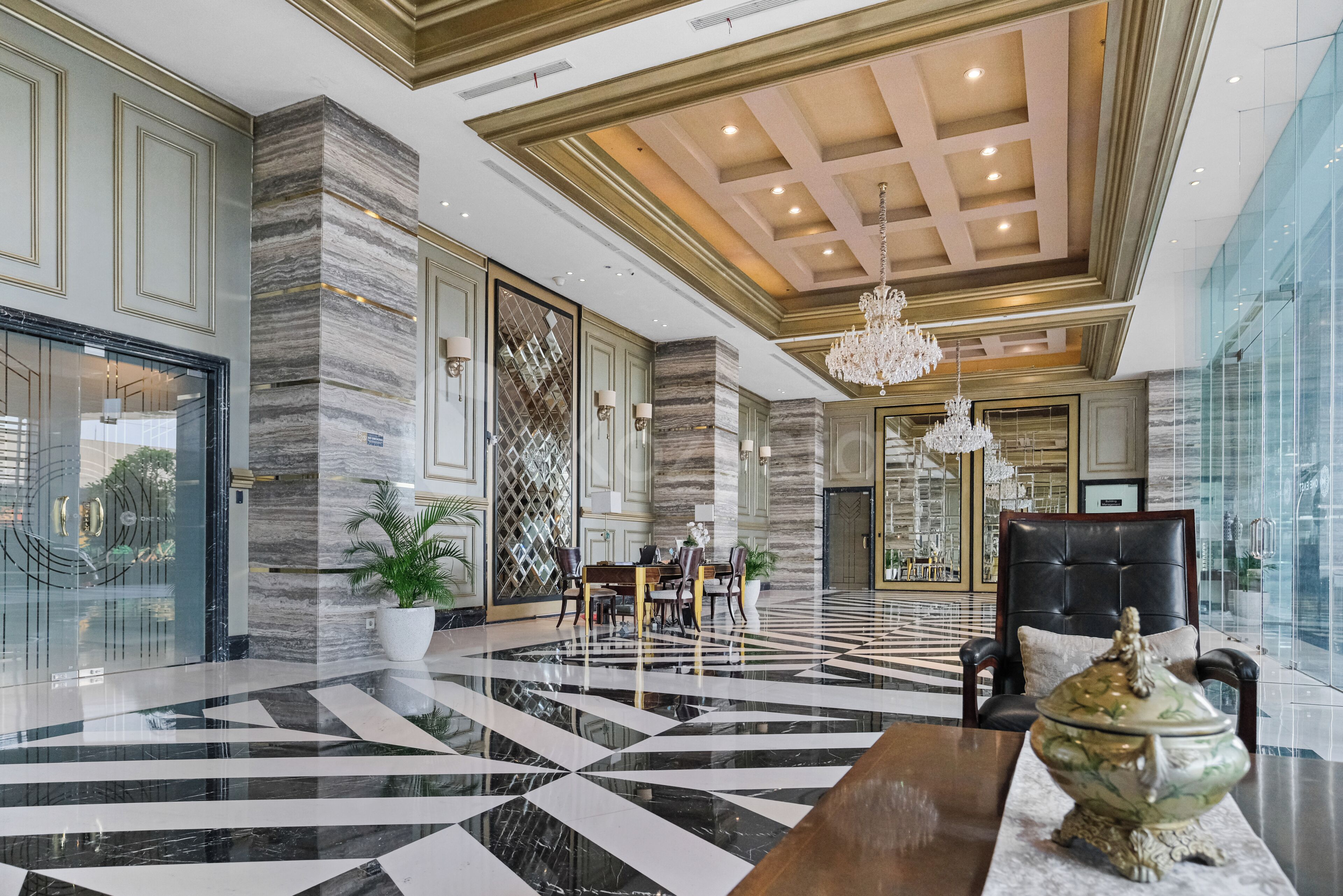 A spacious lobby with a marble floor, a chandelier, and a seating area with a table and chairs.