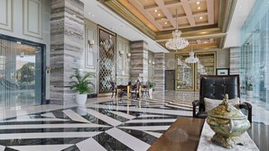 A spacious lobby with a marble floor, a chandelier, and a seating area with a table and chairs. - Cavren by Kozystay - MERR (Surabaya)
