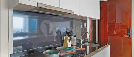 Una cocina moderna con encimera negra, electrodomésticos de acero inoxidable y una puerta roja.