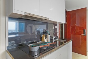 A modern kitchen with a black countertop, stainless steel appliances, and a red door. - Cavren by Kozystay - MERR (Surabaya)